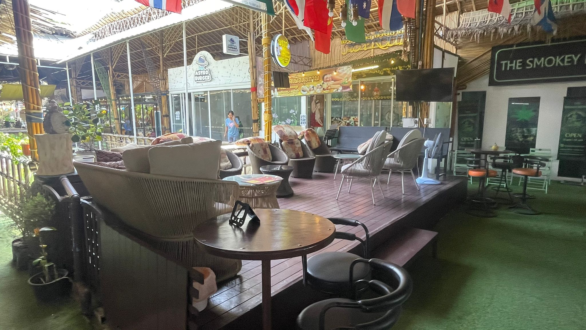 Open-air lounge deck with wicker sofas and world flags overhead